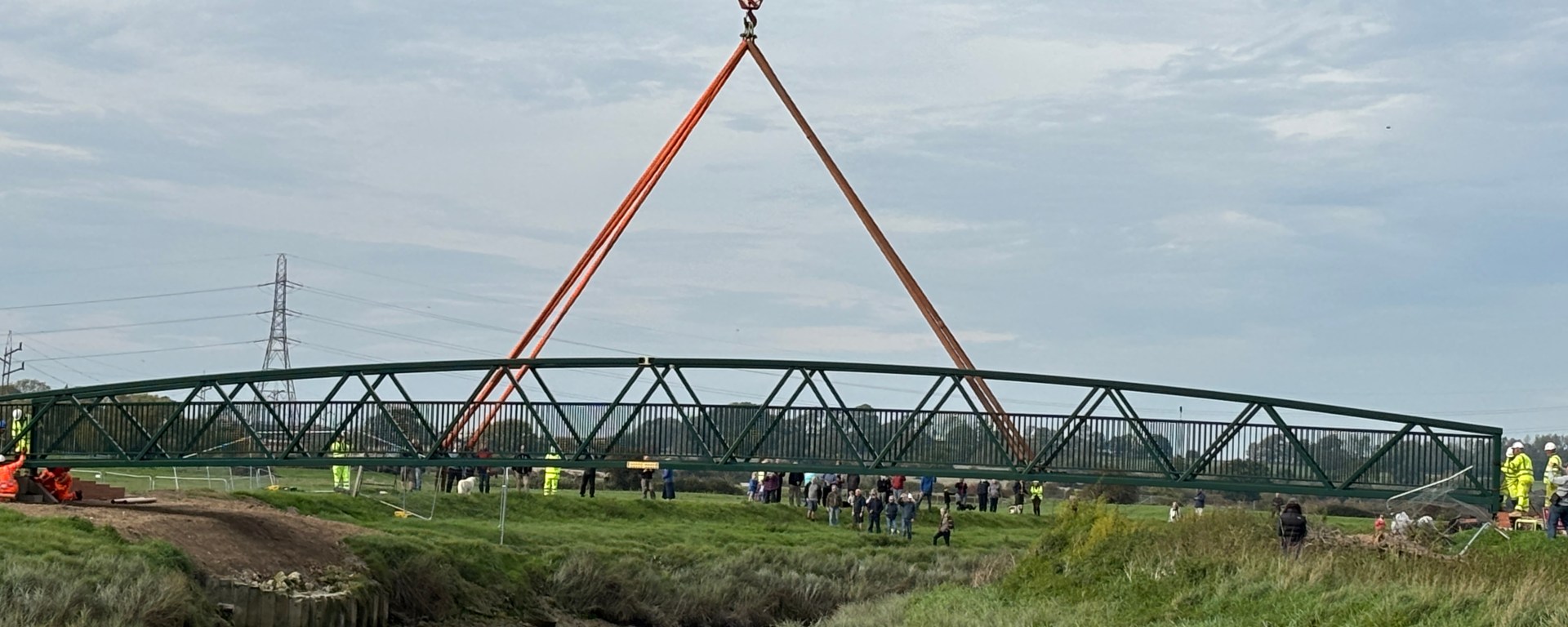 bridge being lowered into place over a river by a crane.