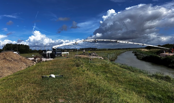 Reference photograph for a painting. Shows a deep blue sky and river banks with a white bridge-like object stretching across the river.
