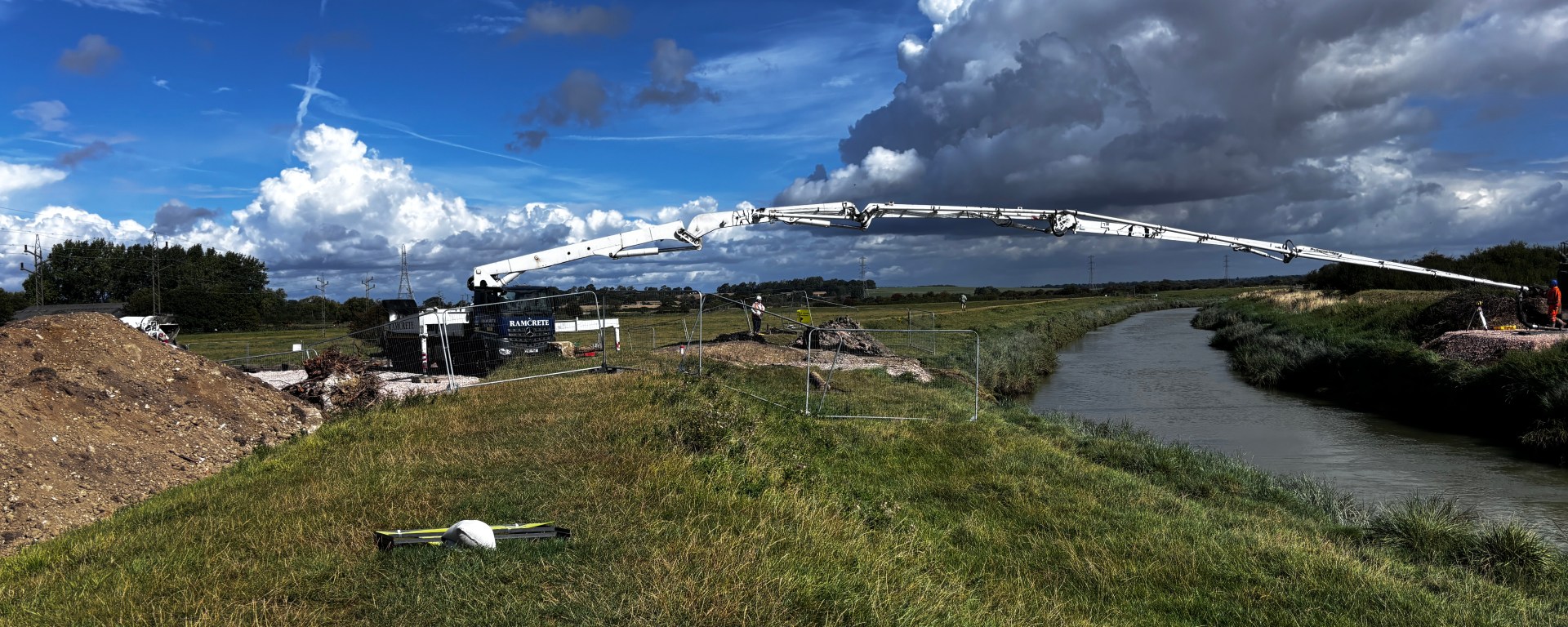 Reference photograph for a painting. Shows a deep blue sky and river banks with a white bridge-like object stretching across the river.