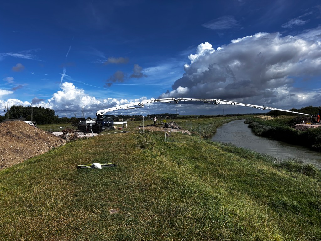 Reference photograph for a painting. Shows a deep blue sky and river banks with a white bridge-like object stretching across the river.