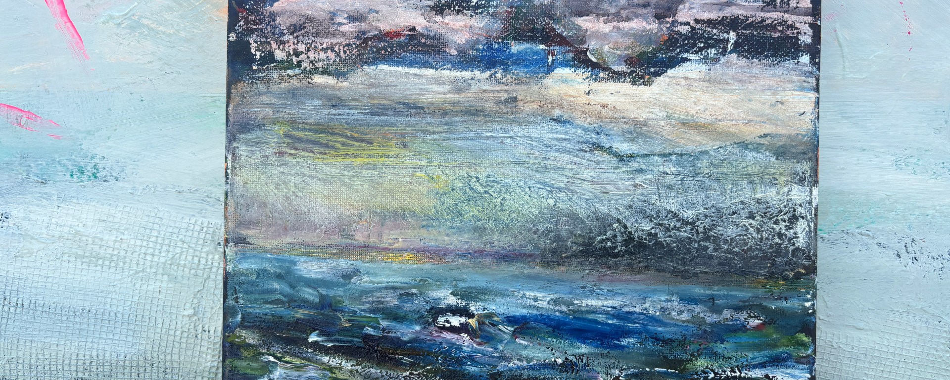 Predominately blue land/sea scape with clouds, hints of a storm, and a sea with a boat.